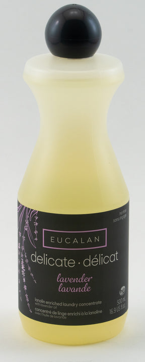 A 16.9 oz bottle of Eucalan Wool Wash is shown. The no-rinse, lanolin-enriched delicate laundry concentrate is lavender-scented. The semi-transparent yellow bottle features a black and lavender label with text in English and French, and contains 100% biodegradable fluid.