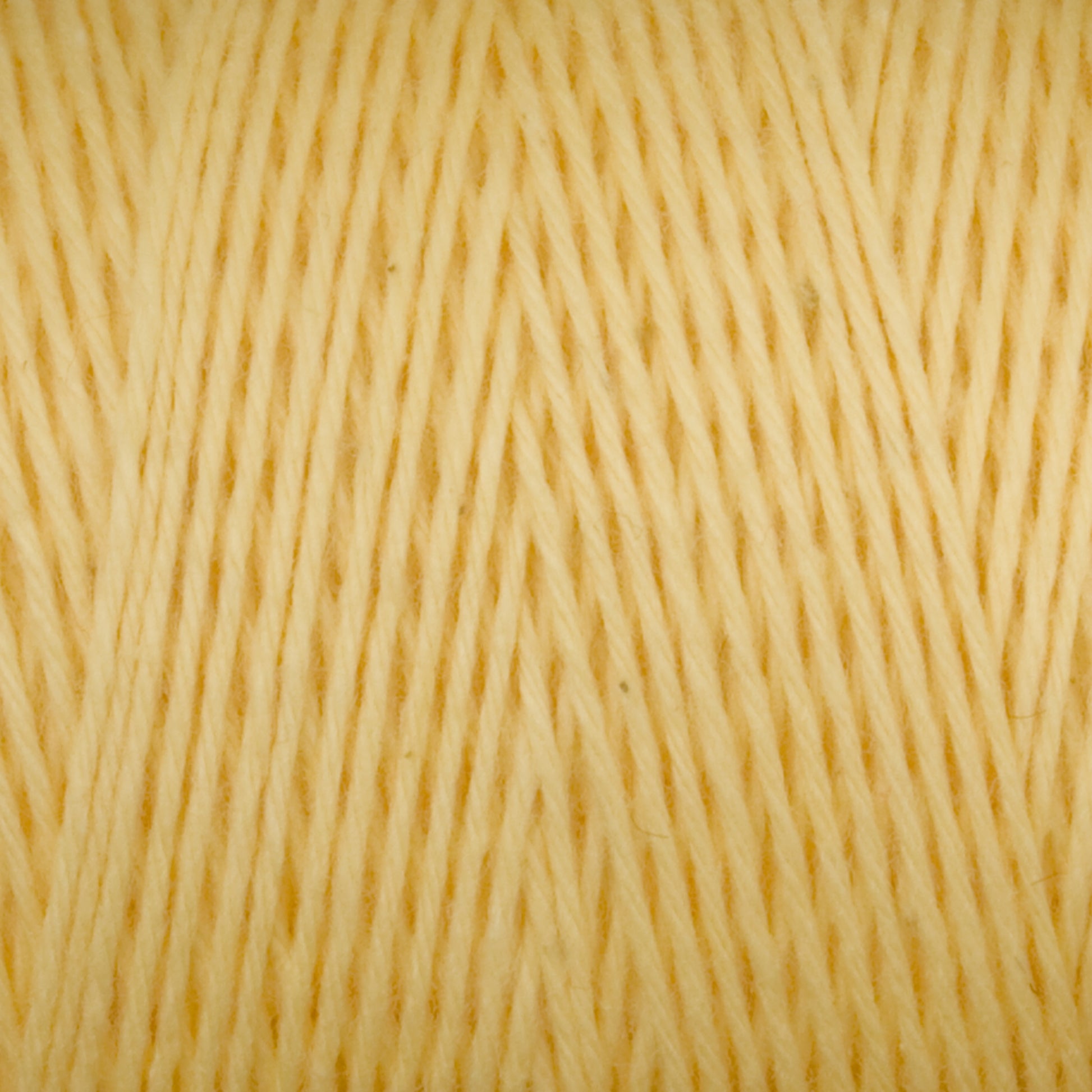 Close-up of a spool of Maurice Brassard's Medium Cotton 16/8 Mop Yarn in yellow, showcasing the texture and tight, uniform arrangement of the fibers. The yarn appears soft and is ideal for knitting, with consistent thickness throughout.