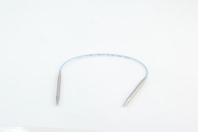 The Addi Turbo Circular Knitting Needles by Skacel are displayed on a pristine white background. These white flexible needles, featuring metallic tips at both ends, look like short circular needles. They appear lightweight and are curved into a loose arc with small printed text on their surface.