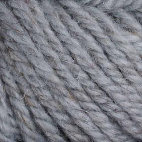 Close-up image of thick, twisted yarn in a pale gray color. The fibers are slightly fuzzy, giving the Halcyon Yarn Classic Rug Wool | Skein by Caledonian Dye Works a soft and cozy appearance, perfect for weavers seeking high-quality rug wool.