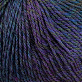 Close-up of a skein of Knitting Fever Painted Desert Yarn by Knitting Fever / Euro Yarns. The super fine weight yarn is twisted and showcases a rich blend of hues, predominantly blues, purples, and greens with long color changes that create a gradient effect. The texture appears soft and slightly fuzzy, suggesting it is likely made of wool or a wool blend.