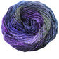 A close-up of a Noro Silk Garden ball of yarn by Knitting Fever / Euro Yarns, featuring a blend of colors, including shades of purple, blue, and green. This silk/wool blend yarn has a slightly fuzzy texture and is tightly wound, displaying a gradient effect throughout.