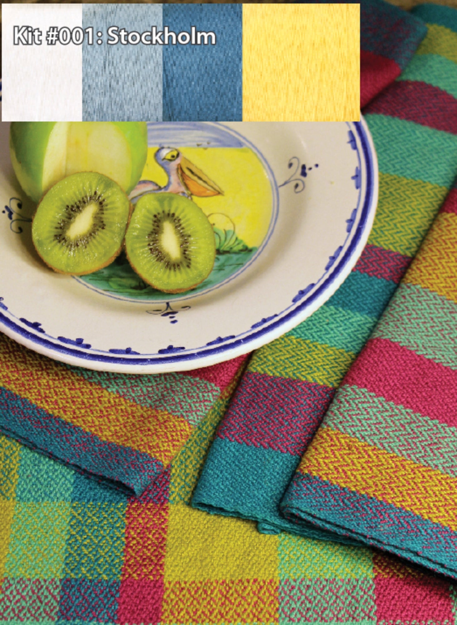 A colorful setup featuring a plate with a pelican illustration and two kiwi slices, placed on a table covered with vibrant, multicolored woven textiles. The caption reads "Kit #001: Stockholm," showcasing the Halcyon Yarn Organic Cottolin Tea Towel Kit designed for a 4 shaft loom, complete with yarn samples in white, grey-blue, teal, and yellow above.