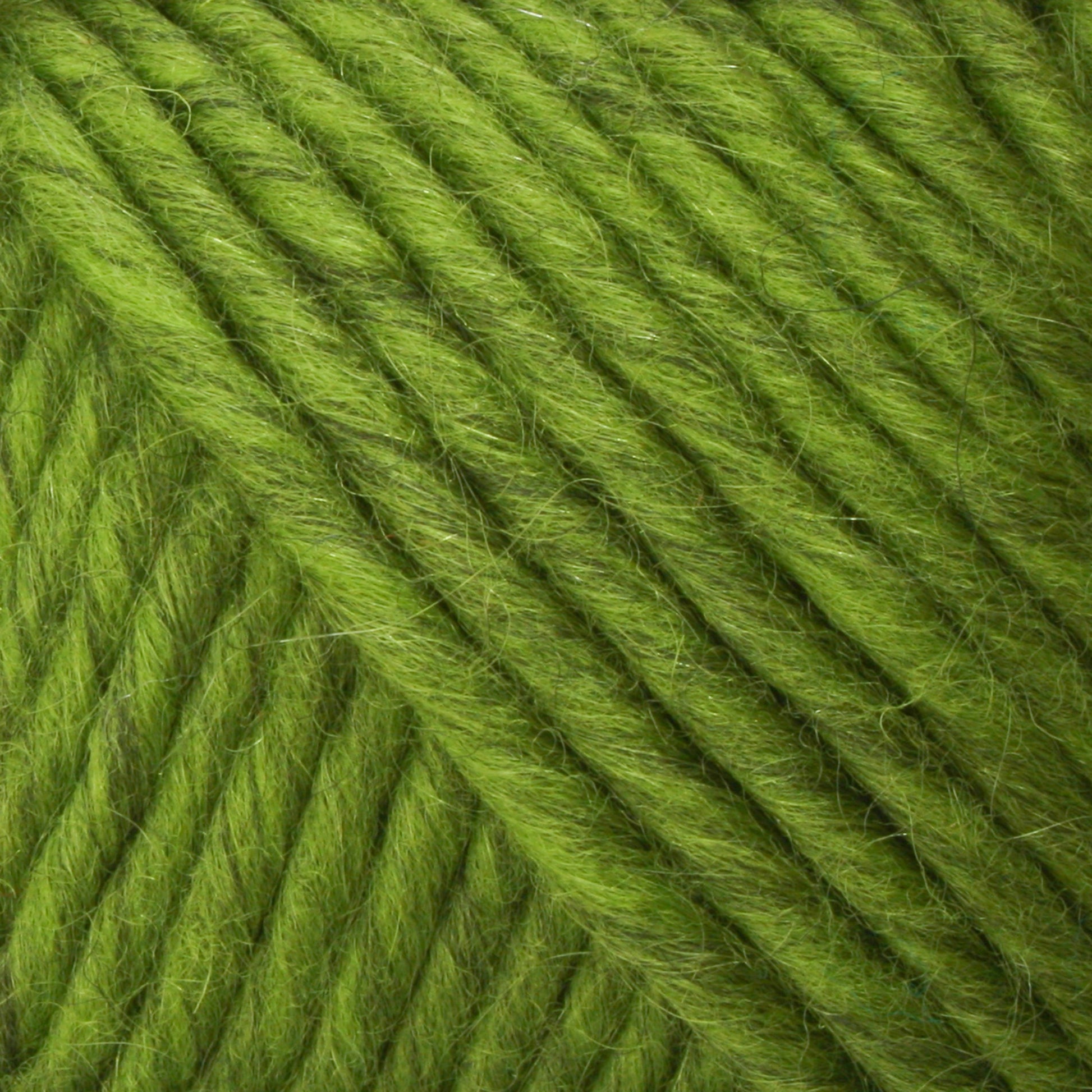 Close-up of tightly wound, vibrant green Lamb's Pride Bulky Yarn by Brown Sheep, showing the texture and details of the fibers. The yarn strands are arranged in a diagonal pattern, reminiscent of those found in woven blankets favored by knitters and crocheters.