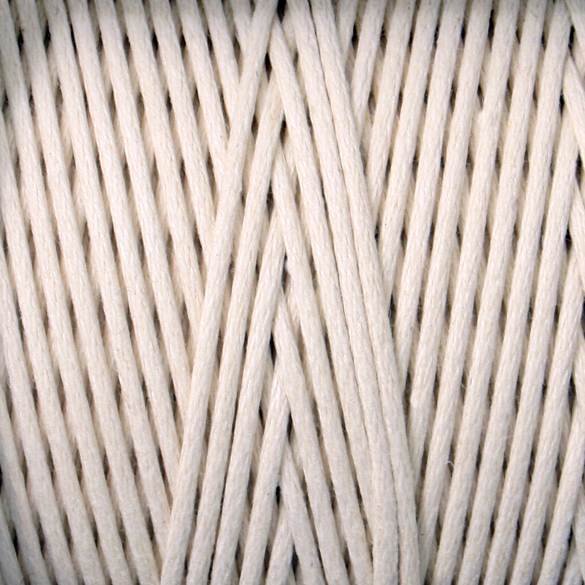 A close-up image of a thick spool of #9 Cotton Lacing Cord from Stuart C. Hurlbert & Co., organized in neat, parallel strands. The texture is clearly visible, showing a tightly twisted, fibrous appearance akin to that used by braided rug artisans. The image emphasizes the material's natural, woven quality similar to cotton rug lacing cord.