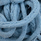 A close-up view of light blue Harrisville Potholder Loops - Traditional Size Mini Pack by Friendly Loom, showcasing intricate loops and textures. The loops, reminiscent of cotton strands on a traditional loom, are tightly intertwined, forming a complex pattern with visible fibers and strands.