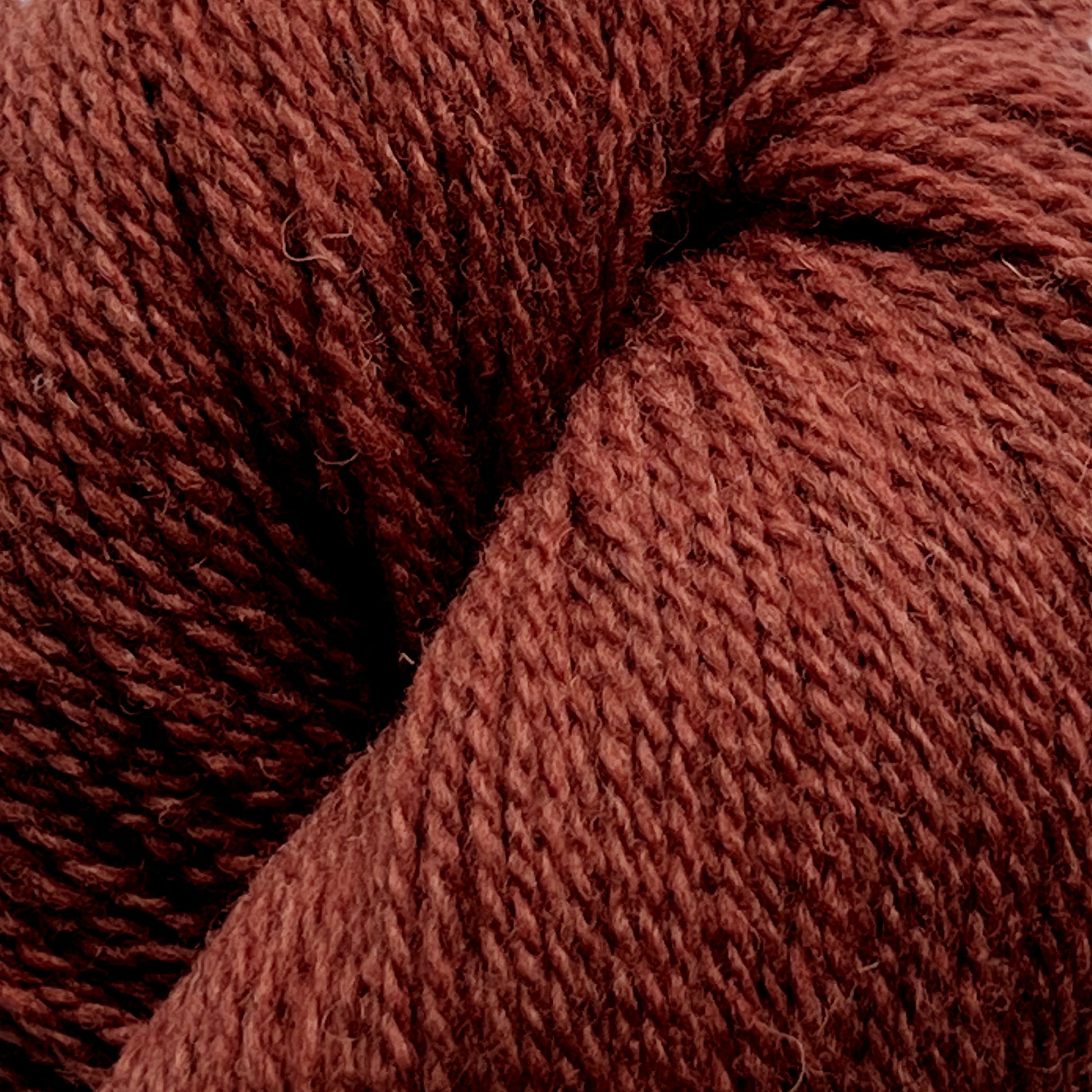 Close-up image of a skein of Patagonia Organic Merino by Juniper Moon Farm from Knitting Fever / Euro Yarns in a deep, warm brown color. The soft, thick yarn fibers appear textured and slightly fuzzy, suggesting its organic Merino wool composition or a high-quality wool blend, ideal for knitting or crocheting garments and accessories.