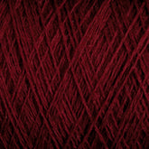 Close-up of JaggerSpun Maine Line 3/8 Yarn in maroon, manufactured by Jagger Brothers, Inc. The worsted spun yarn is tightly wound, forming an intricate pattern of overlapping strands. The texture looks soft and slightly fuzzy, with varying shades of red visible under the lighting.