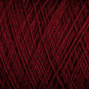 Close-up of JaggerSpun Maine Line 3/8 Yarn in maroon, manufactured by Jagger Brothers, Inc. The worsted spun yarn is tightly wound, forming an intricate pattern of overlapping strands. The texture looks soft and slightly fuzzy, with varying shades of red visible under the lighting.