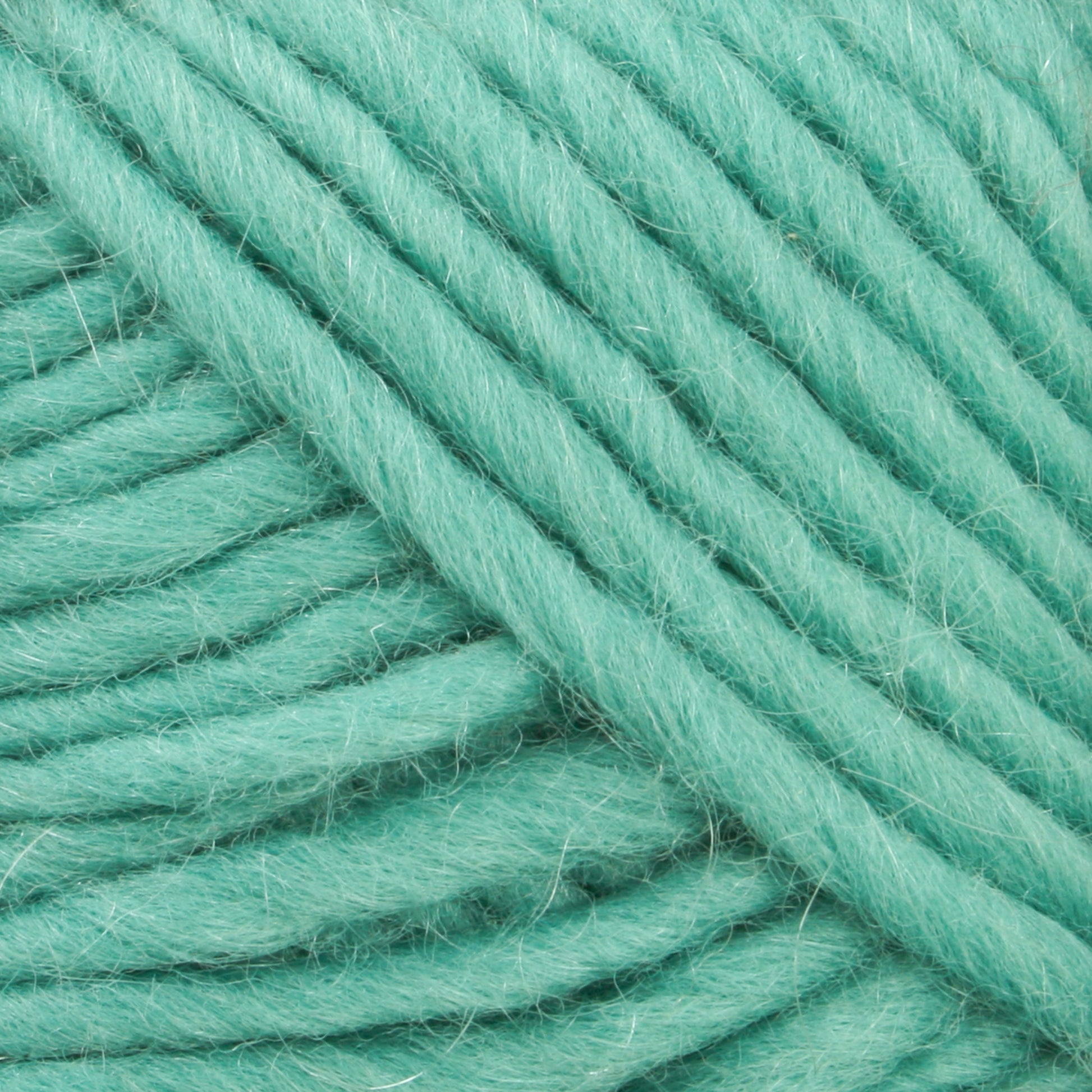 Close-up image of tightly wound, thick, mint-green Lamb's Pride Bulky Yarn by Brown Sheep. The texture appears soft and slightly fuzzy, with individual fibers visible. The yarn is arranged in a neat and orderly fashion, perfect for knitters and crocheters seeking to create intricate details in woven blankets or Icelandic sweaters.