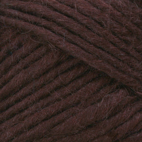 Close-up image of Lamb's Pride Bulky Yarn by Brown Sheep, featuring dark brown fibers tightly wound with a slightly fuzzy texture. The yarn is arranged to highlight the individual strands and their thickness, making it ideal for knitters and crocheters crafting cozy Icelandic sweaters.