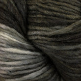 Close-up of a skein of Malabrigo Silky Merino by Malabrigo Yarn in shades of dark green, gray, and off-white. The merino yarn strands are tightly twisted, creating a textured, layered appearance. The colors blend seamlessly, with lighter hues accentuating the darker tones.