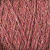 Close-up image of red and pink heathered Harrisville Shetland Yarn - Unwashed Cones. The fibers are intertwined, showcasing a mix of colors and textures, creating a cozy and inviting appearance suitable for knitting lightweight blankets or Fair Isle knitting designs by Harrisville Designs.