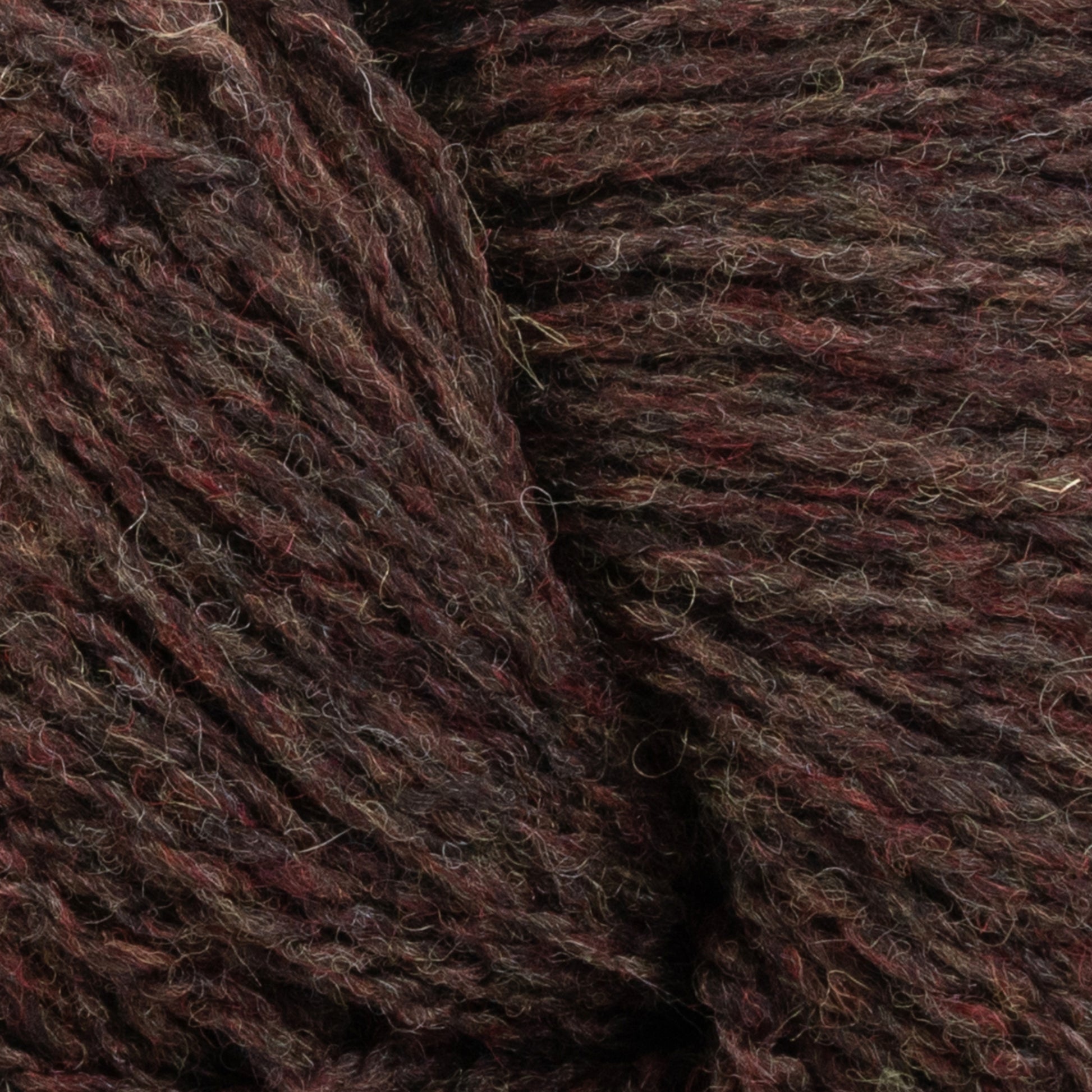 Close-up of dark brown and black wool yarn with hints of reddish-brown, showing its texture and fibers. The thick, tightly spun Patagonia Organic Merino by Juniper Moon Farm from Knitting Fever / Euro Yarns is GOTS certified, making it perfect for knitting or crocheting projects.