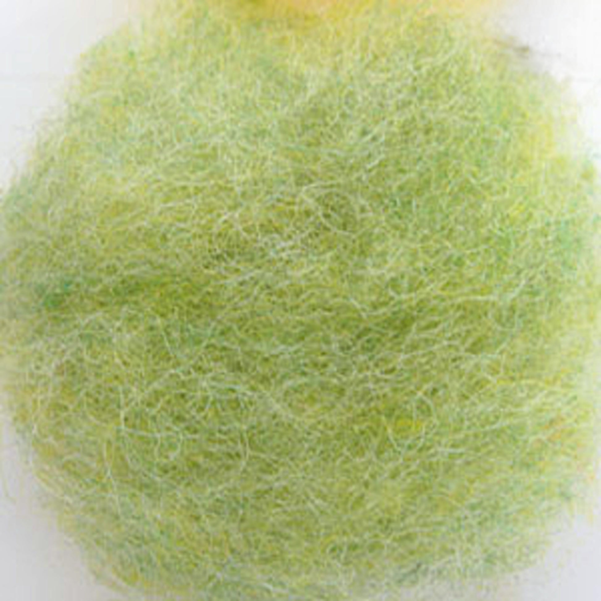 Close-up of a round, fluffy ball of fibrous material in shades of green and yellow, resembling Harrisville Dyed & Carded Wool Fiber by Harrisville Designs. The texture appears soft and slightly tangled, perfect for felting projects with its heathered colors.