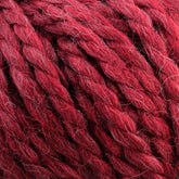 Close-up of thick, red strands of Baby Alpaca Grande by Plymouth, twisted together. This bulky weight yarn from Plymouth Yarn Co. features a slightly fuzzy texture with hints of different shades of red, giving it a rich, ultra-soft multi-dimensional appearance.