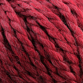 Close-up of thick, red strands of Baby Alpaca Grande by Plymouth, twisted together. This bulky weight yarn from Plymouth Yarn Co. features a slightly fuzzy texture with hints of different shades of red, giving it a rich, ultra-soft multi-dimensional appearance.