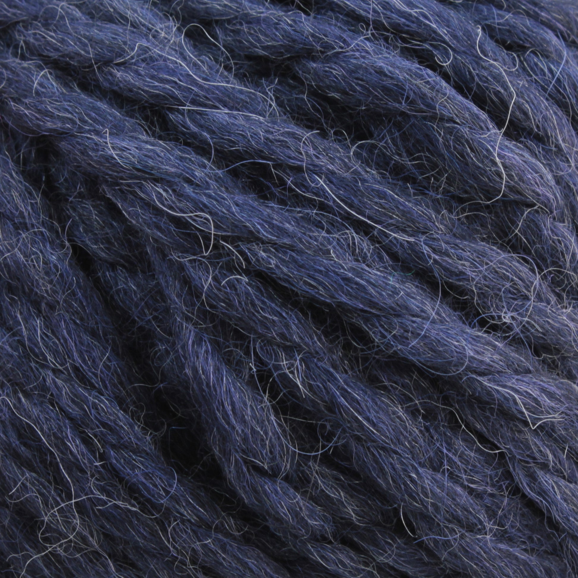 A close-up image of thick, dark blue Baby Alpaca Grande by Plymouth yarn with a slightly fuzzy texture. The strands are loosely woven together, showcasing some individual fibers. This ultra-soft, bulky weight yarn from Plymouth Yarn Co. has a rich and consistent color throughout, promising cozy warmth and comfort.