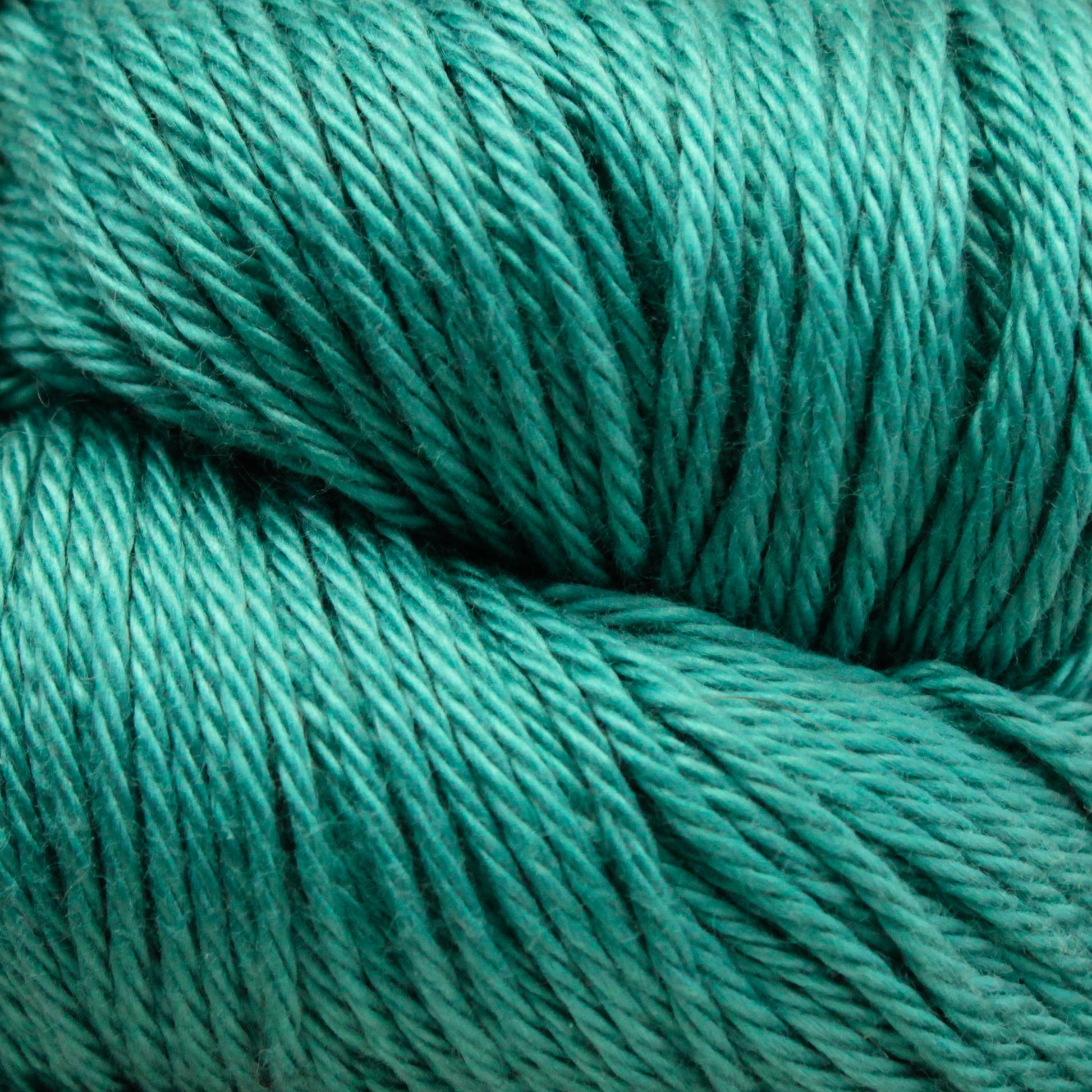 Close-up of a bundle of turquoise Cascade Ultra Pima Cotton Yarn from Cascade Yarns. The strands are tightly wound together, showcasing a smooth and consistent texture. The vibrant color and neatly coiled Peruvian Pima Cotton fibers indicate yarn suitable for knitting or crocheting projects.