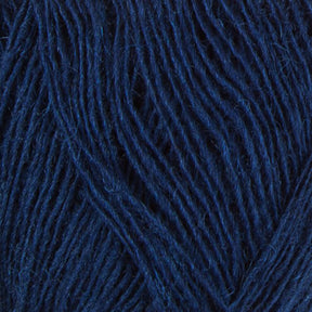 Close-up of Einband Lopi navy blue yarn strands by Berroco, Inc. The image showcases the intertwined fibers exhibiting a rich, deep blue hue with a soft texture, perfect for lace knitting. This detailed view highlights the yarn's thickness and intricate weave pattern.