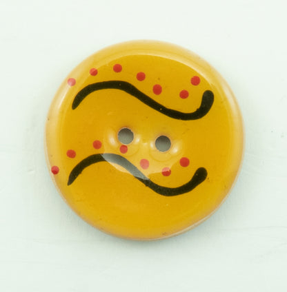 The Coco Enamel Fa la la Button by Buttons Etc. is a round, yellow coconut button with a 1 1/8" diameter featuring two center holes. It flaunts a decorative design with red dots and black curved lines on its slightly glossy surface.