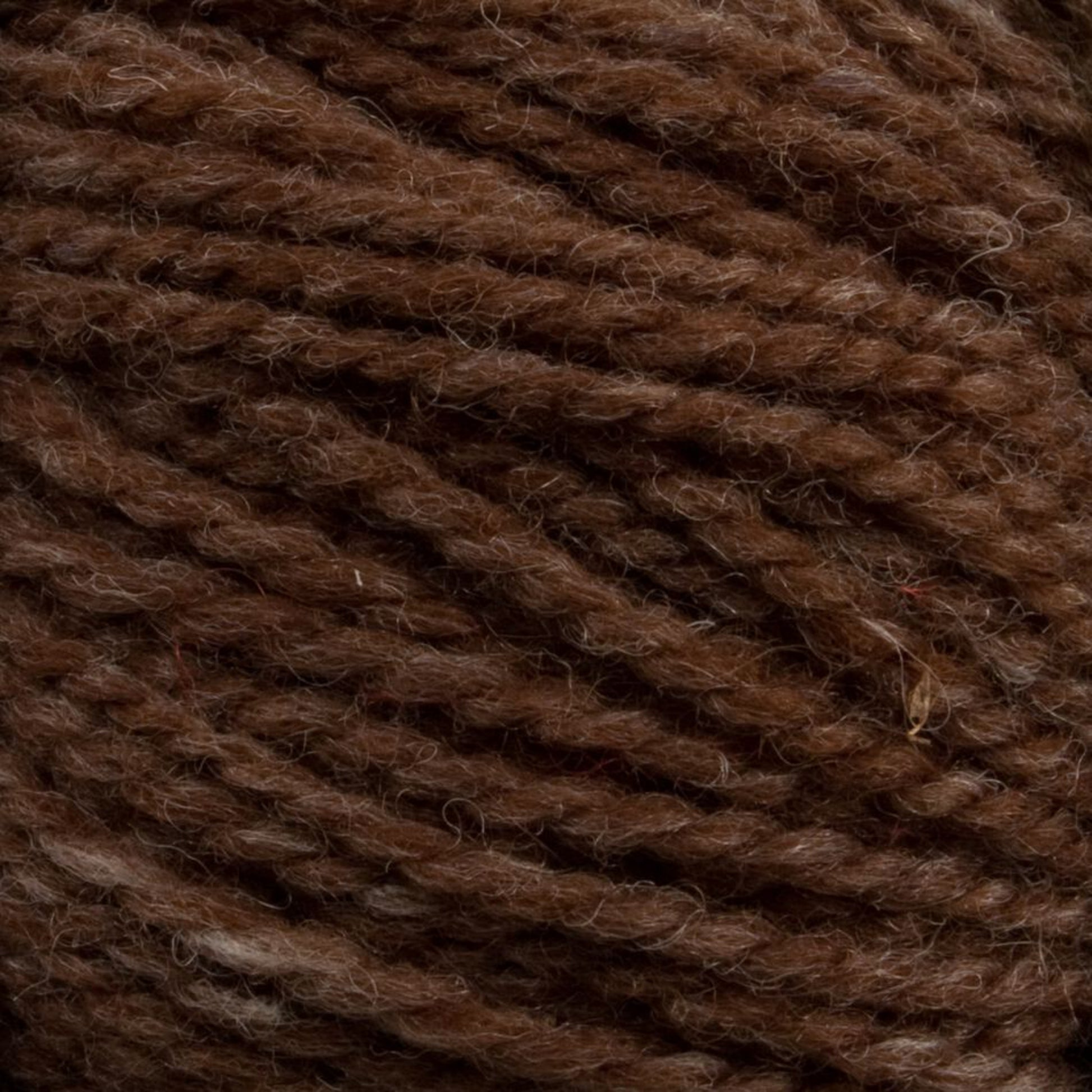 A close-up view of Briggs & Little's Tuffy Canadian Sock Yarn, showcasing its finely textured and intertwined fibers. The yarn features a rich blend of lighter and darker brown tones, creating a natural and appealing look—ideal for knitting cozy winter socks.