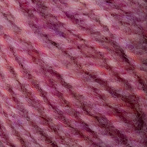 Close-up of a skein of Bartletts Maine Wool - Sport yarn from Bartlettyarns featuring a blend of pink, purple, and red hues. The yarn is thick and textured, showcasing a mix of light and dark shades that create a marbled effect. The fibers appear soft and fluffy.