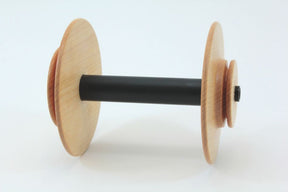 The Schacht Spinning Wheel Bulky Bobbin by Schacht Spindle Co. features two light-colored wooden discs on either end, connected by a black cylindrical shaft, all set against a plain white background.