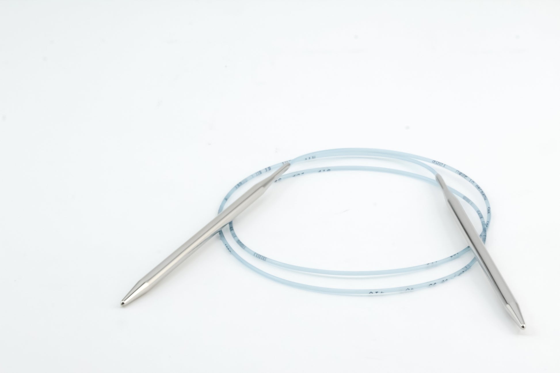 A pair of Skacel Addi Turbo Circular Knitting Needles, featuring a connecting blue plastic cable, are displayed against a plain white background.