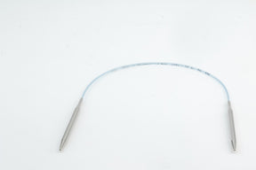 A pair of Addi Turbo Circular Knitting Needles by Skacel lies curved on a clean white background, their smooth, tapered ends resembling short circular needles. The main body consists of thin, translucent tubes with text printed along their length.