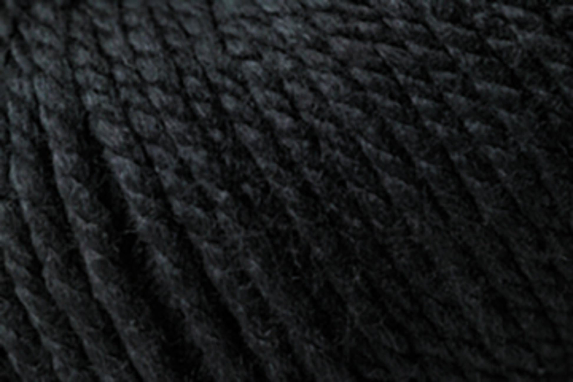 Close-up of tightly wound, dark-colored yarn. The texture appears super soft and slightly fuzzy, with individual strands clearly visible, showing the twisted fibers that make up the yarn. This Jo Sharp Silkroad Ultra by Kingfisher Yarn & Fibre is perfect for cozy winter accessories with its deep charcoal or black hue.