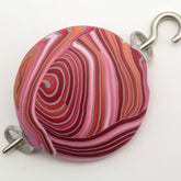 Introducing the **Ball-O-Yarn Pomegranate Shawl Pin by Bonnie Bishoff Designs** from **Bonnie Bishoff**. This charming, round accessory showcases vibrant red, pink, white, and orange swirled patterns crafted from polymer clay. It is elegantly attached to a silver hook and loop on each side, set against a plain white background—ideal for securing shawls or adding a touch of flair to knitted wearables.