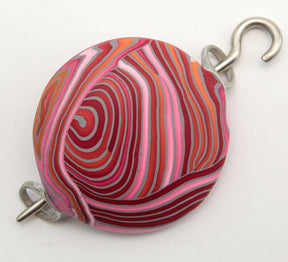 Introducing the **Ball-O-Yarn Pomegranate Shawl Pin by Bonnie Bishoff Designs** from **Bonnie Bishoff**. This charming, round accessory showcases vibrant red, pink, white, and orange swirled patterns crafted from polymer clay. It is elegantly attached to a silver hook and loop on each side, set against a plain white background—ideal for securing shawls or adding a touch of flair to knitted wearables.