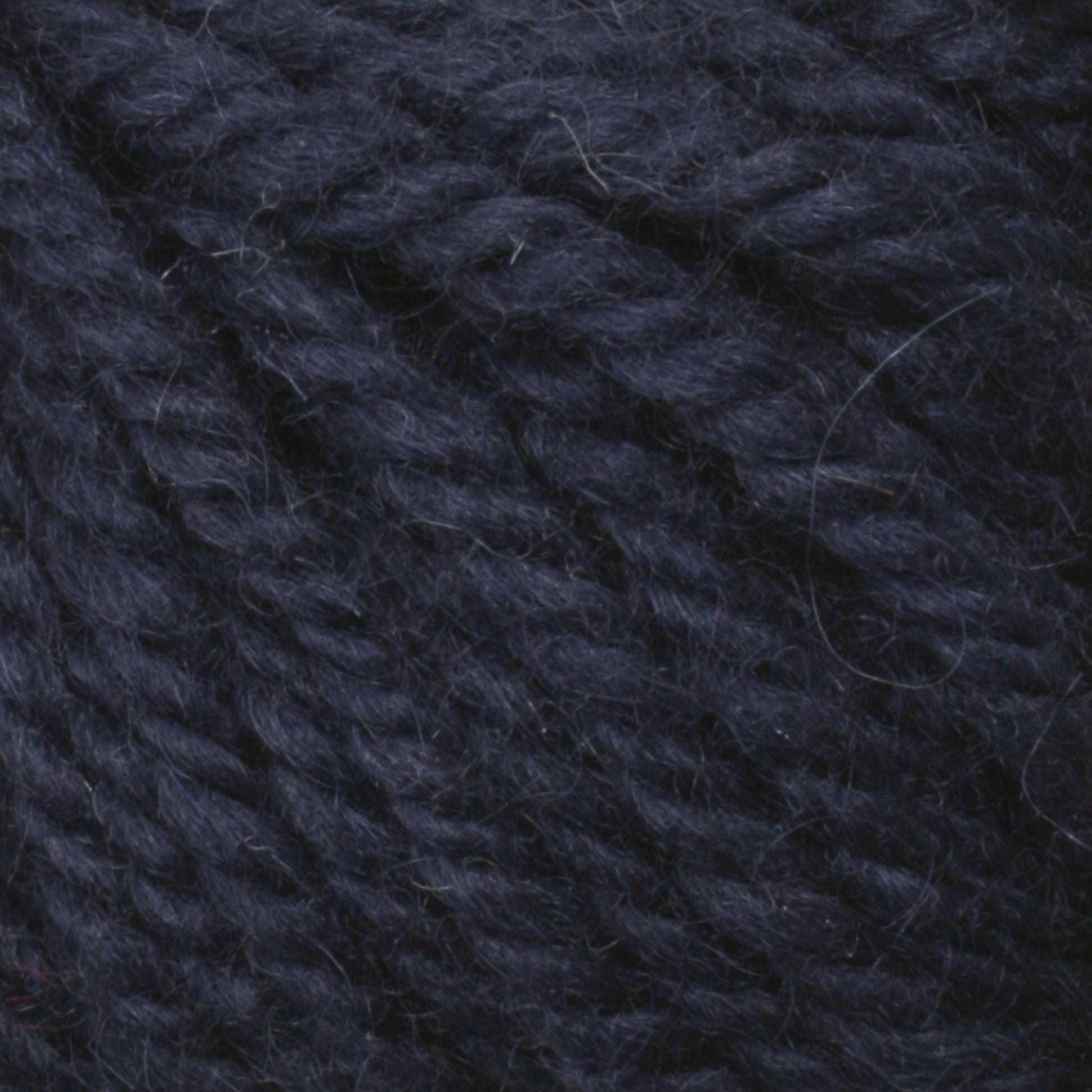 Close-up image of Halcyon Yarn Classic Rug Wool | Strand in dark blue by Caledonian Dye Works, showcasing a tightly twisted texture. The yarn appears soft and woolly, ideal for knitting or crocheting. Hand-dyed for a rich tone, the fibers are slightly fuzzy, adding a slight halo effect to the strands—perfect for rug weavers seeking Classic Rug Wool quality.