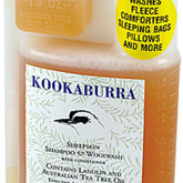 A 500 ml bottle of Kookaburra Woolwash by ABL Development, Inc., featuring a black bird silhouette and labeled with lanolin and Australian tea tree oil. A yellow sticker indicates it washes fleece, comforters, sleeping bags, pillows, and more.