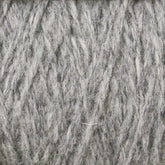 A close-up of Harrisville Designs' Harrisville Highland - Cones in unscoured gray wool yarn, showcasing the interwoven fibers with a slightly fuzzy texture. The strands are tightly wound together, creating a dense and uniform appearance. The color is a mix of light and dark gray tones, reminiscent of classic Harrisville Highland yarns.