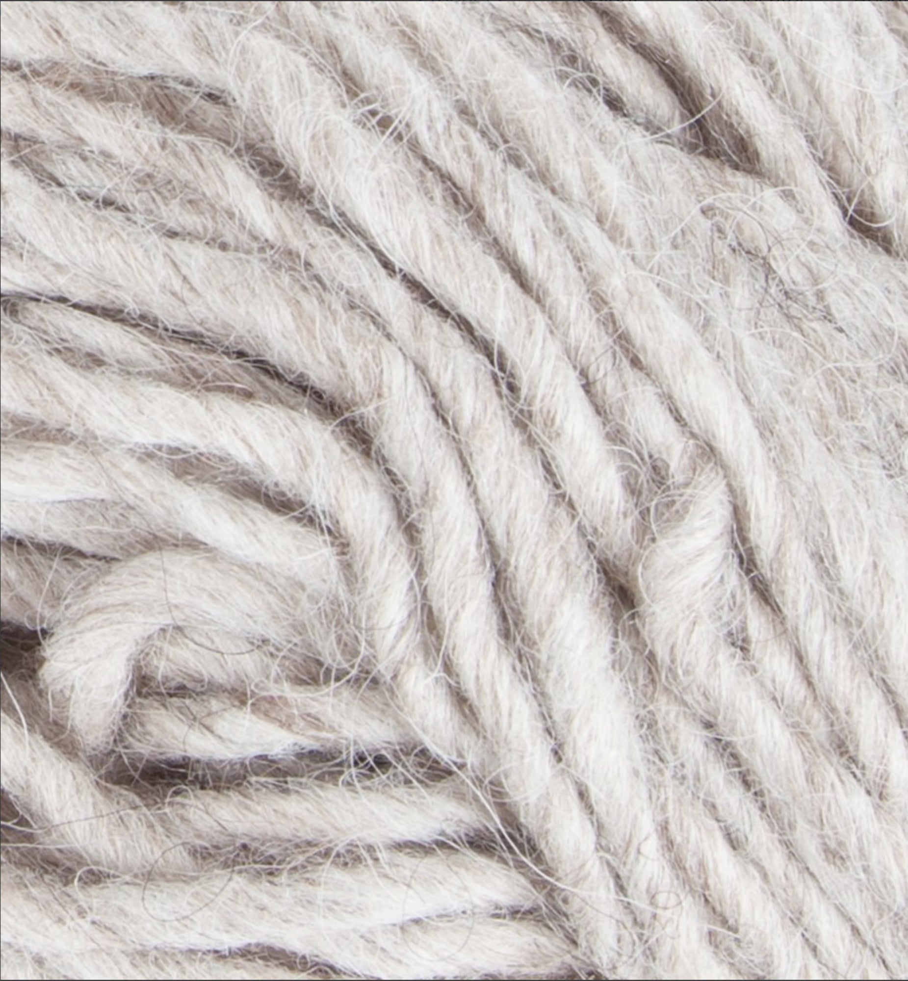 Close-up image of thick, off-white Jöklalopi (Bulky Lopi) yarn by Berroco, Inc., coiled together to showcase its natural colors and rustic handmade charm, with visible texture and fibers perfect for chunky winter sweaters.