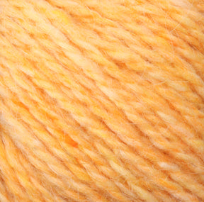 A close-up of a soft, fluffy Peace Fleece Yarn by Harrisville Designs, showcasing an orange and yellow blend with a slightly fuzzy texture. The intertwining threads create a marbled effect, highlighting the gradient blend of warm tones in this worsted weight knitting wool and mohair mix.