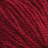 Close-up image of Halcyon Deco Rug Wool strands tightly wound together, revealing the texture and detail of the maroon red fibers. This thick and soft 100% wool yarn from Caledonian Dye Works exhibits a slightly fuzzy surface, making it perfect for creating durable yet versatile projects like Deco rug yarn pieces.