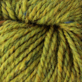 A close-up image of Peace Fleece Yarn by Harrisville Designs, showcasing thick, twisted strands in a variegated mix of green and yellow with occasional flecks of blue. The texture looks soft and fuzzy, underlining its worsted weight knitting perfection.