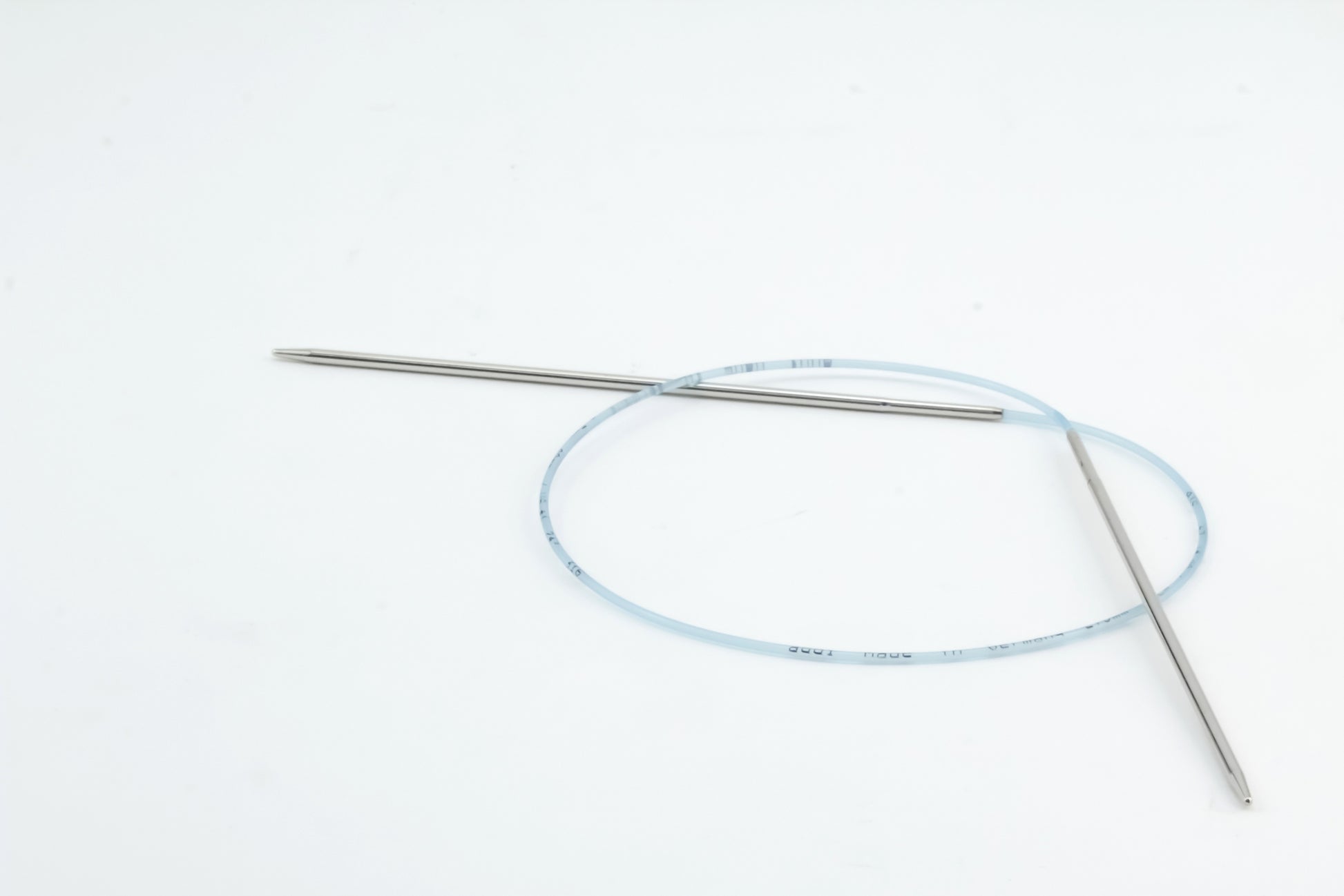 A pair of Addi Turbo Circular Knitting Needles by Skacel, featuring two stainless steel tips with one slightly longer than the other, is displayed against a plain white background. The flexible blue cable ensures precision and safety in knitting projects, similar to how detailed medical guidewires perform in delicate medical procedures.