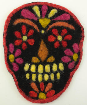 A vibrant felt sugar skull decoration set against a white background, featuring a black base adorned with bright red, yellow, and pink floral patterns, along with a yellow nose and yellow and white teeth. This intricate design captures the traditional Day of the Dead aesthetic perfectly. It would make an excellent project using The Felting Studio’s Needle Felting Tapestry Kits.