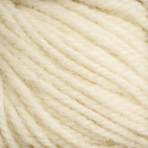 A close-up view of multiple strands of soft, cream-colored yarn from Caledonian Dye Works' Halcyon Deco Rug Wool, showcasing their twisted texture and fluffy fibers. This 100% wool yarn appears cozy and thick, suitable for knitting or crochet projects. Its versatile nature makes it perfect for creating a variety of handmade items.