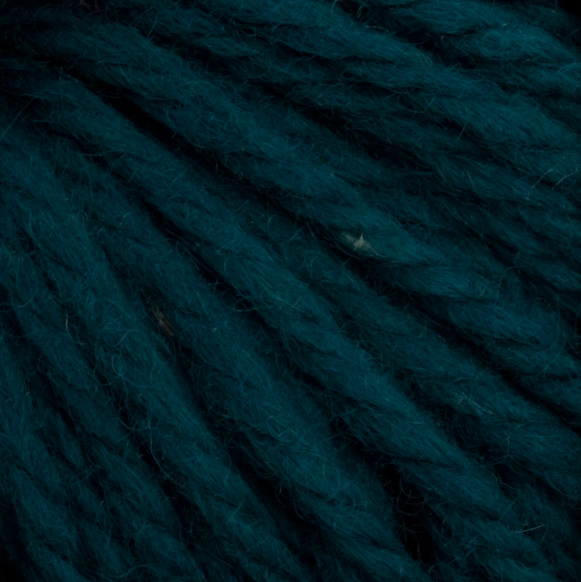 Close-up image of deep teal-colored yarn. The strands are thick and slightly textured, woven together to form a dense, fibrous surface. This hand-dyed Halcyon Yarn Classic Rug Wool | Strand by Caledonian Dye Works is rich and vibrant, highlighting the intricate details of the yarn fibers—perfect for rug weavers seeking quality material.