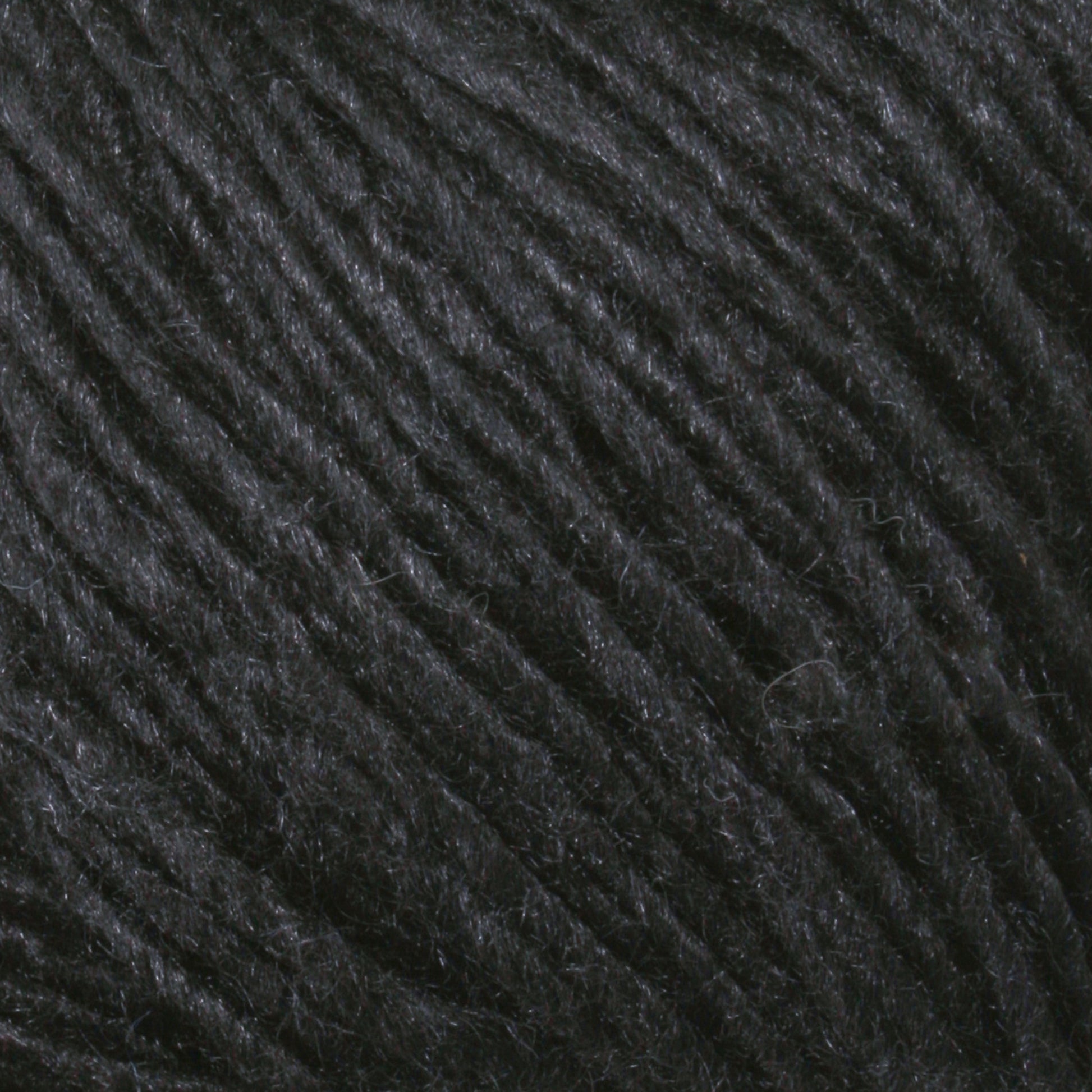 Close-up of Malabrigo Silky Merino, showcasing its fibrous texture. The yarn strands are tightly wound together, creating a soft and slightly fuzzy appearance. The texture and dark color suggest it could be used for knitting or crocheting dense fabric items, perfect for those looking to create rich, dark-colored projects.