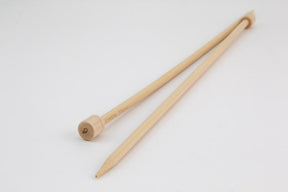 Two bamboo knitting needles from Accessories Unlimited rest on a white surface. One needle's tapered end points towards the camera, while the other ends in a flat knob with a small decorative mark or logo. These 12" Bamboo Single-Point Knitting Needles are perfect for various handcraft projects.