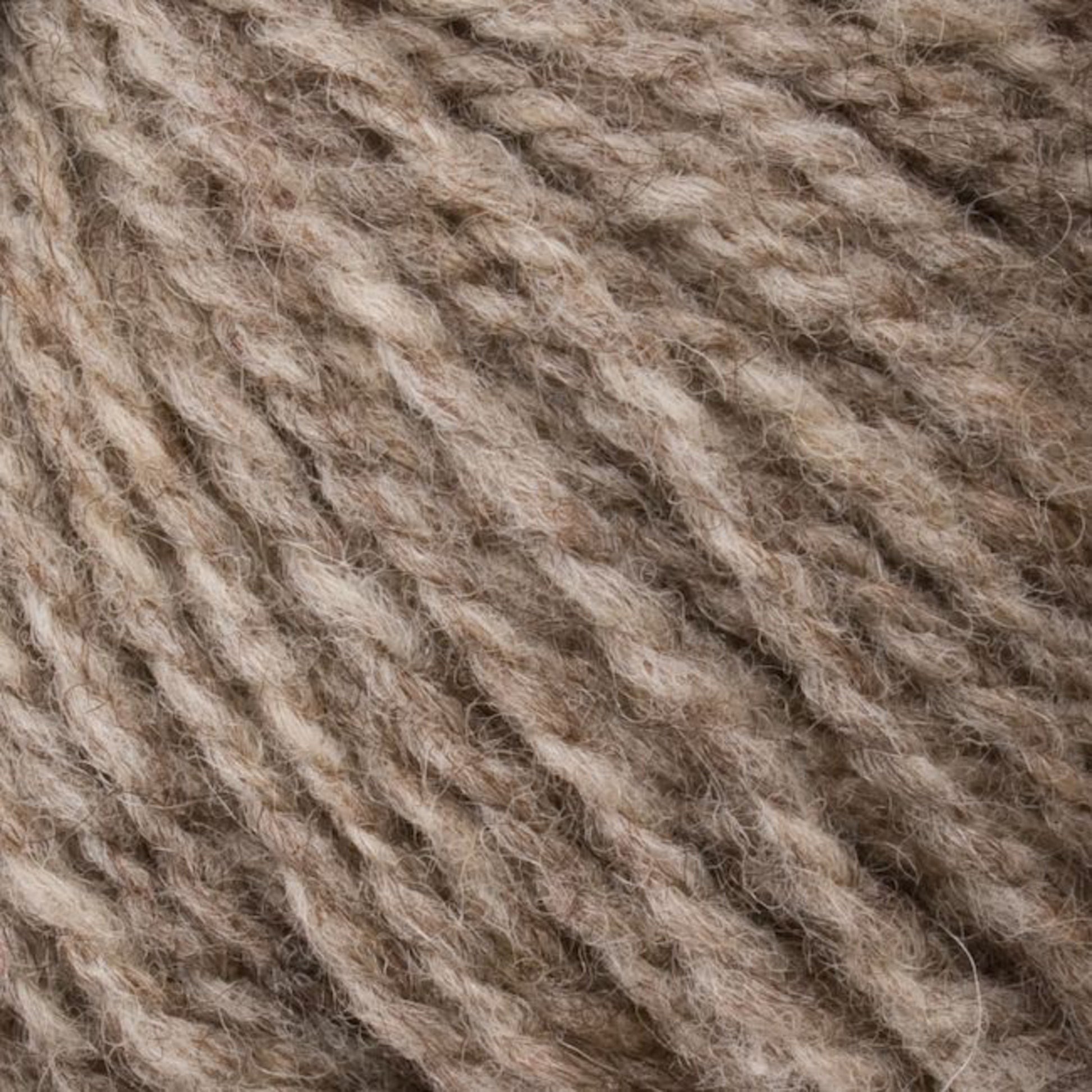 Close-up of soft, textured beige yarn fibers twisted into strands, creating a cozy and natural appearance. The Bartlettyarns "Bartletts Maine Wool - Sport" yarn appears fluffy and inviting, suitable for knitting or crafting projects.