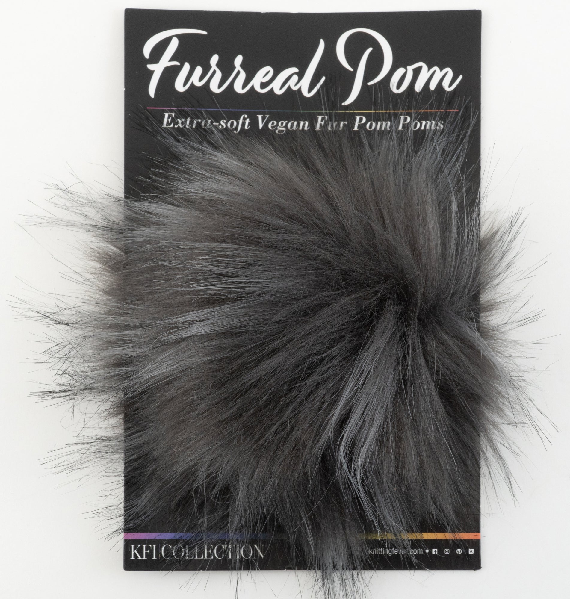 A packaging of Furreal Pom by KFI from Knitting Fever / Euro Yarns shows a fluffy, extra-soft vegan fur pom pom in a grayish-black color. The background features black cardboard with the text "Furreal Pom" and "Extra-soft Vegan Fur Pom Poms.