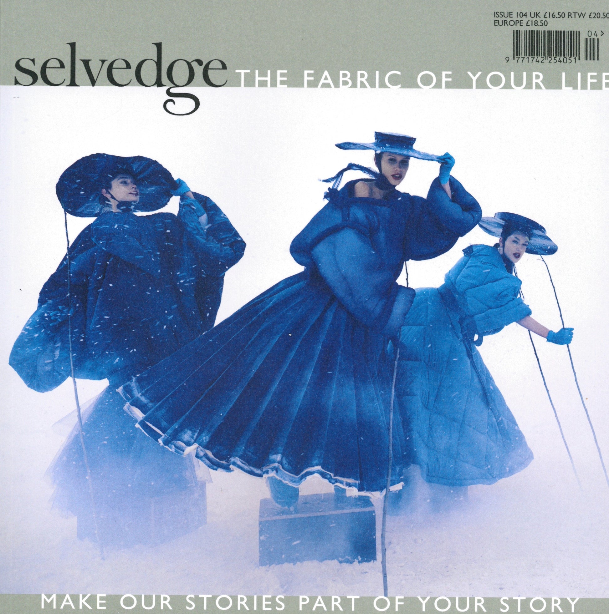 An image of the magazine cover titled "Selvedge - Issue 104: Keeping Warm" by the brand Selvedge. It features three women wearing artful, oversized blue winter clothing and hats made from luxurious yak fibre, posing dramatically in a snowy landscape. The tagline reads, "Make our stories part of your story.