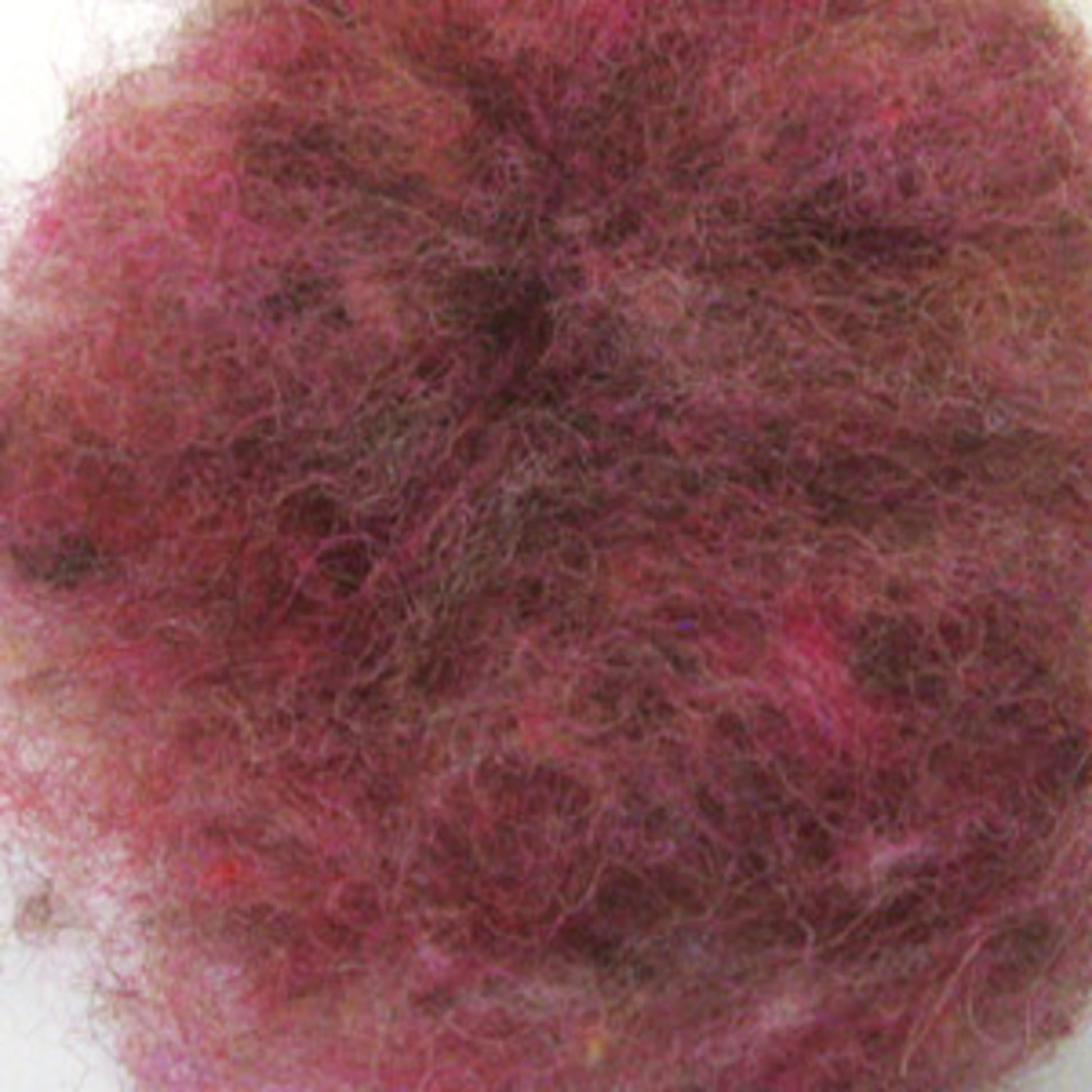 A close-up of a tangled mass of fibers, primarily featuring shades of red, pink, and brown. The texture appears fuzzy and uneven, resembling a clump of Harrisville Dyed & Carded Wool Fiber from Harrisville Designs with heathered colors.